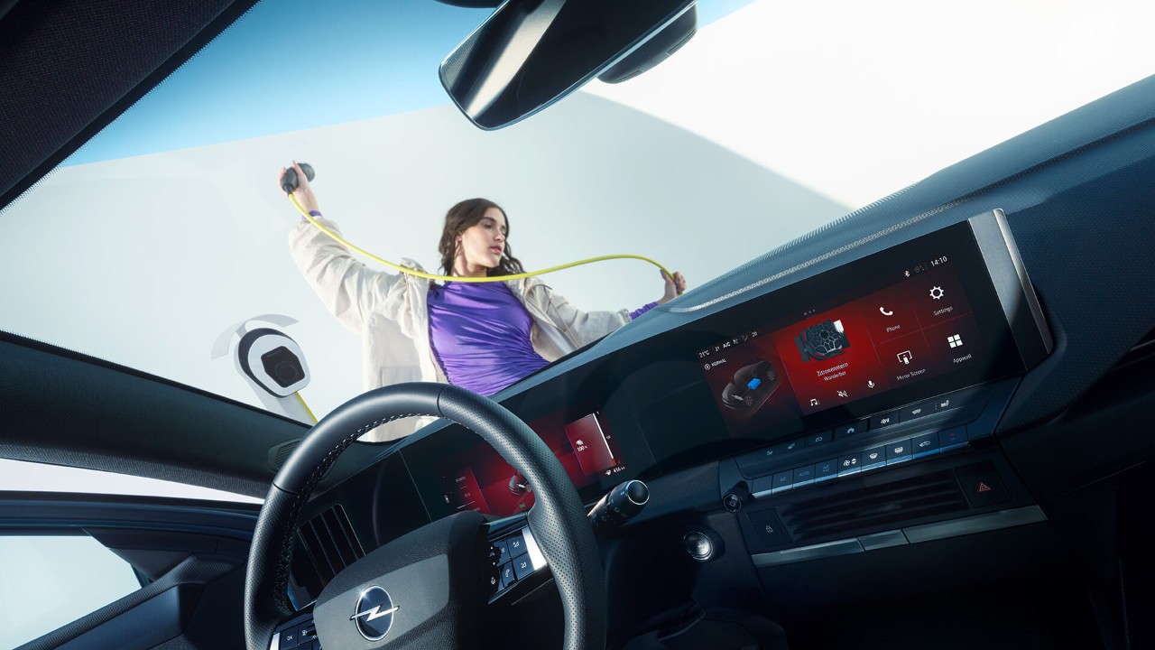 Close-up van het interieur van een Opel Astra Sports Tourer Electric met een vrouw die een EV-oplaadkabel vasthoudt